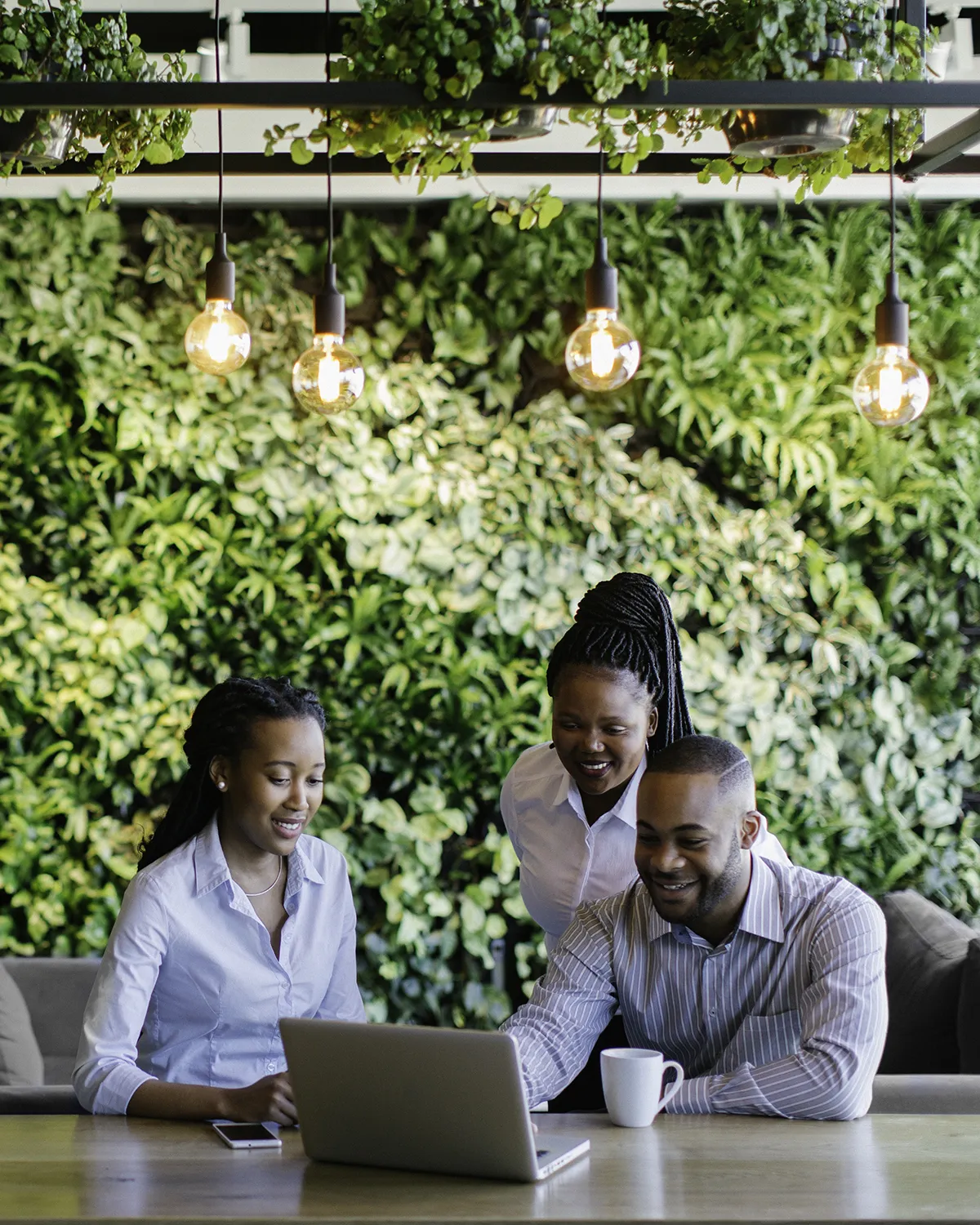 Employees collaborating near a plant wall, highlighting the benefits of plants in the workplace.