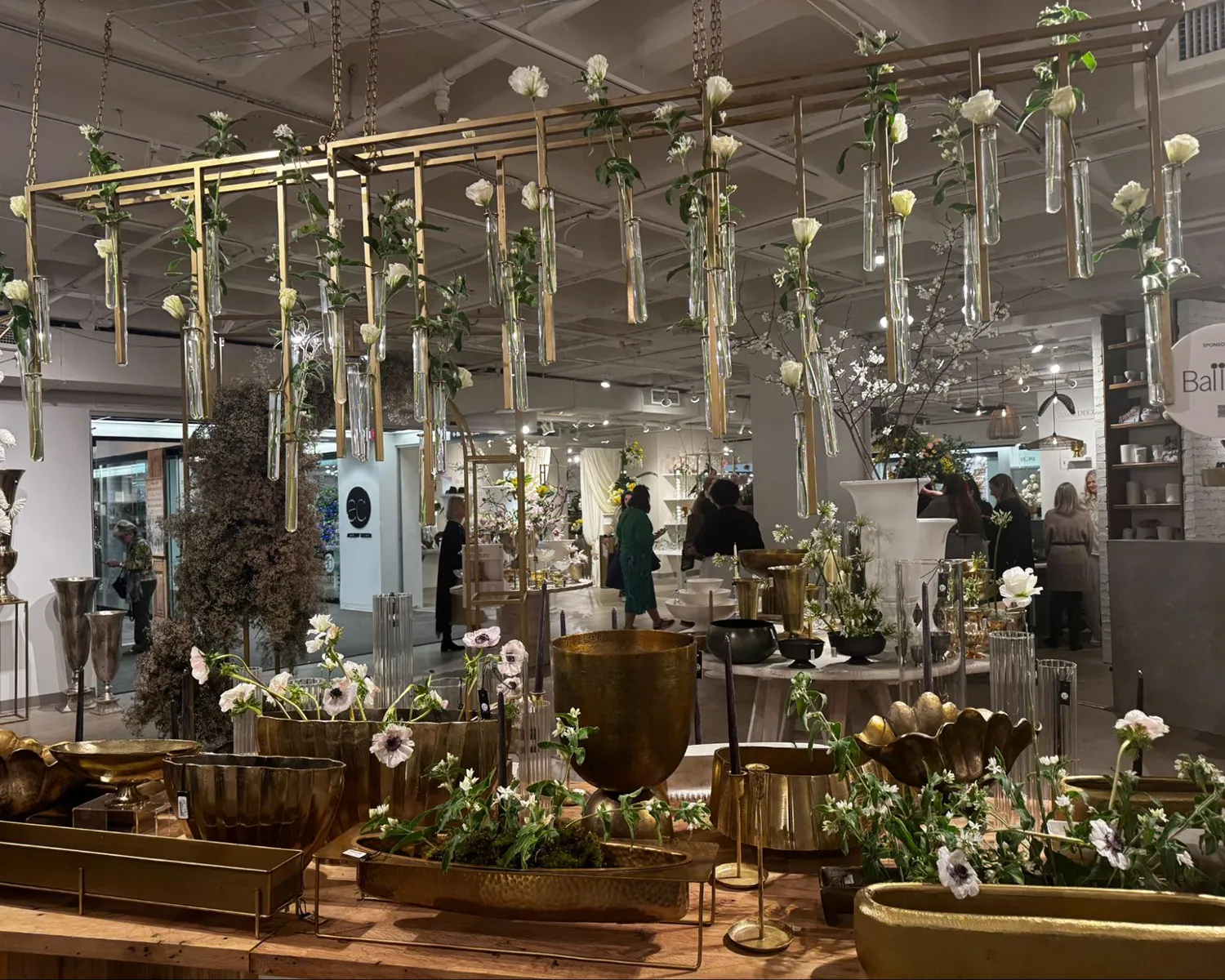 Gold planters and a hanging floral installation with glass tubes.
