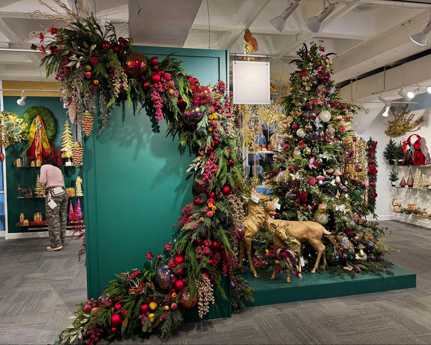 Holiday installation with a green wall and deep red ornament garland.