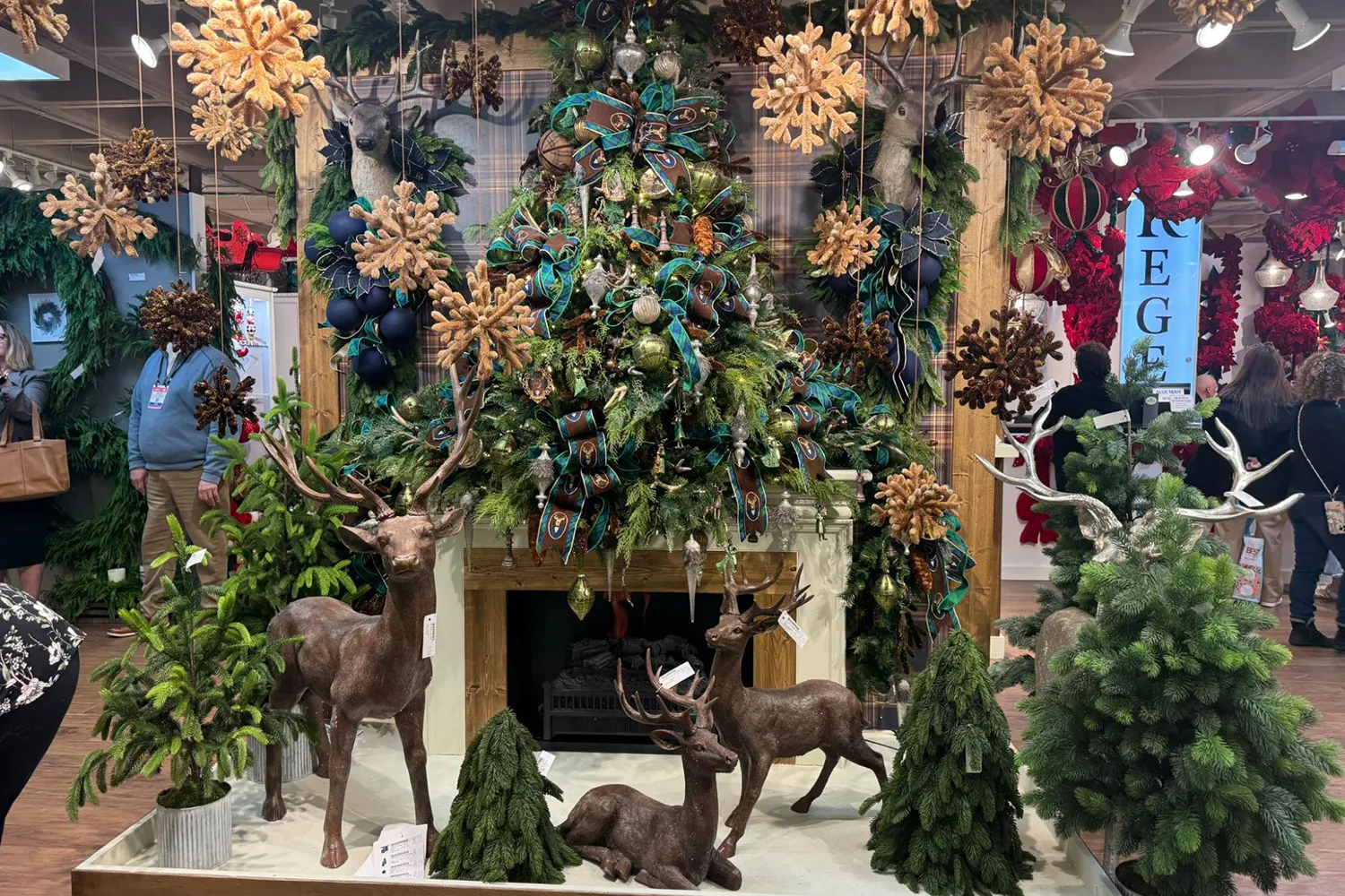 A rustic holiday display featuring bronze deer, plaid ribbons, and a fireplace mantel, representing the vintage nostalgia movement in current office design trends.