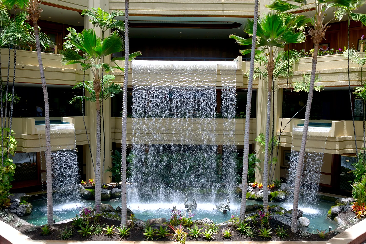 A hotel lobby implementing biophilic design principles with a waterfall and indoor plants.