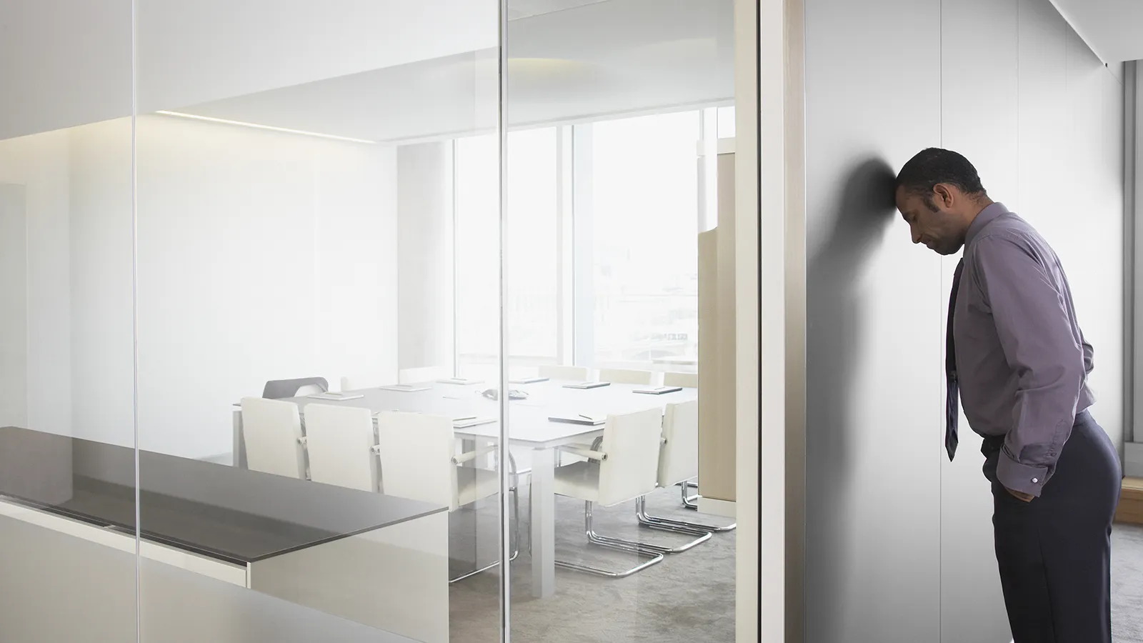 An office worker experiencing the stressful effects of nature deficit disorder in a dull, grey corporate environment.