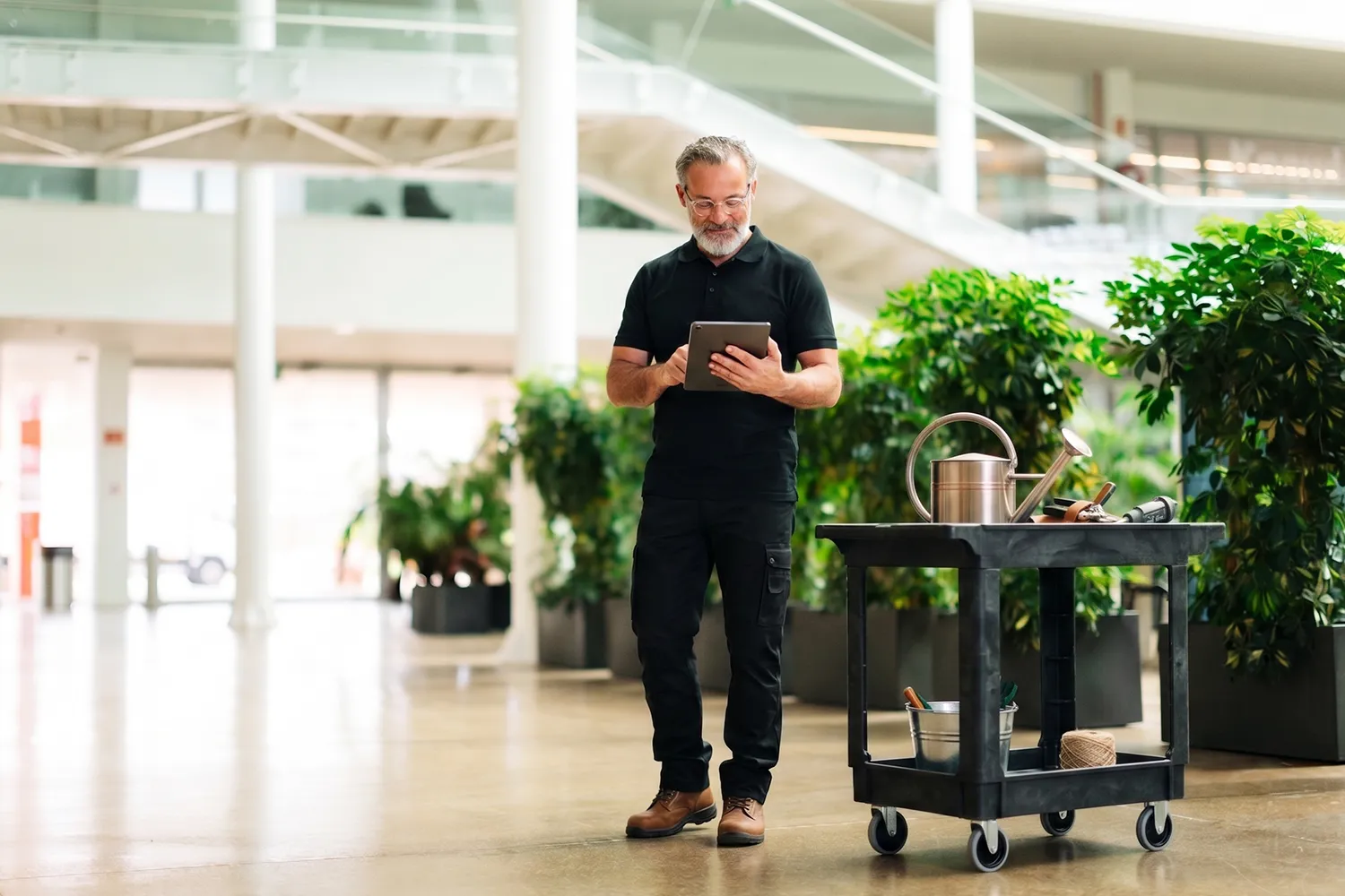 Commercial plant maintenance service technician inspecting plants in a modern office lobby.