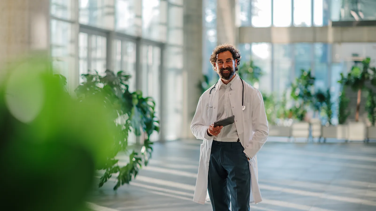 Healthcare Interior Plant Maintenance Doctor smiling at the handiwork of interior plant maintenance technician, plants around the healthcare facility.