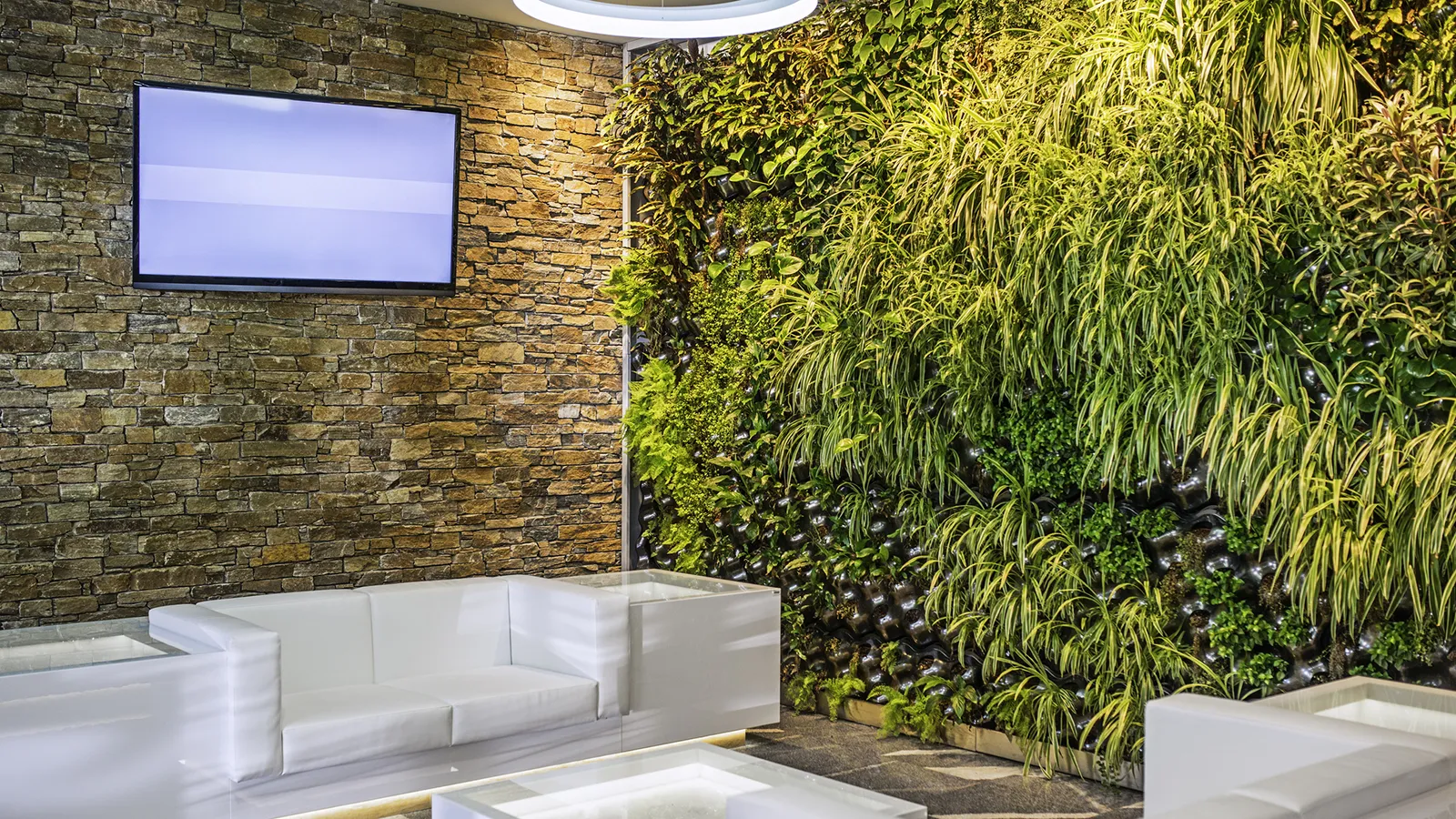 Modern building lobby with white lounge furniture, a brick feature wall, and integrated vertical greenery.